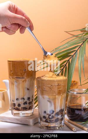 Boba dalgona Kaffee. Trendiges asiatisches Latte-Morgengetränk mit Instant-Kaffee und Tapioka-Perlkugeln, thailändisches Schaumcocktail-Glas im Sommer in der Sonne Stockfoto