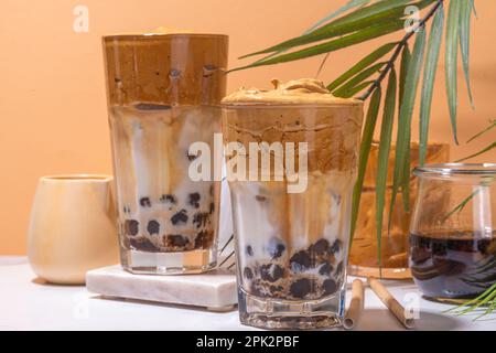 Boba dalgona Kaffee. Trendiges asiatisches Latte-Morgengetränk mit Instant-Kaffee und Tapioka-Perlkugeln, thailändisches Schaumcocktail-Glas im Sommer in der Sonne Stockfoto