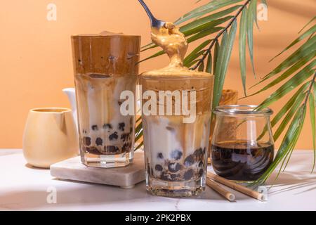 Boba dalgona Kaffee. Trendiges asiatisches Latte-Morgengetränk mit Instant-Kaffee und Tapioka-Perlkugeln, thailändisches Schaumcocktail-Glas im Sommer in der Sonne Stockfoto
