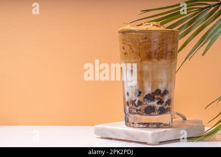Boba dalgona Kaffee. Trendiges asiatisches Latte-Morgengetränk mit Instant-Kaffee und Tapioka-Perlkugeln, thailändisches Schaumcocktail-Glas im Sommer in der Sonne Stockfoto