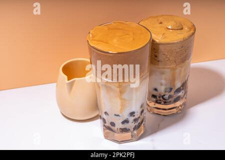 Boba dalgona Kaffee. Trendiges asiatisches Latte-Morgengetränk mit Instant-Kaffee und Tapioka-Perlkugeln, thailändisches Schaumcocktail-Glas im Sommer in der Sonne Stockfoto