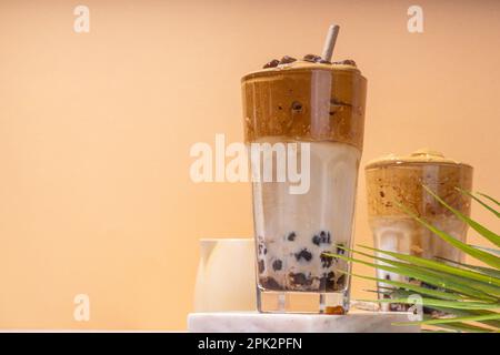 Boba dalgona Kaffee. Trendiges asiatisches Latte-Morgengetränk mit Instant-Kaffee und Tapioka-Perlkugeln, thailändisches Schaumcocktail-Glas im Sommer in der Sonne Stockfoto