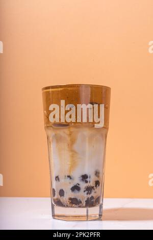 Boba dalgona Kaffee. Trendiges asiatisches Latte-Morgengetränk mit Instant-Kaffee und Tapioka-Perlkugeln, thailändisches Schaumcocktail-Glas im Sommer in der Sonne Stockfoto