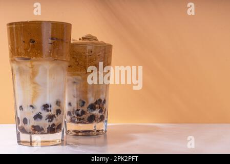 Boba dalgona Kaffee. Trendiges asiatisches Latte-Morgengetränk mit Instant-Kaffee und Tapioka-Perlkugeln, thailändisches Schaumcocktail-Glas im Sommer in der Sonne Stockfoto