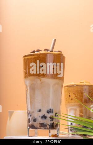 Boba dalgona Kaffee. Trendiges asiatisches Latte-Morgengetränk mit Instant-Kaffee und Tapioka-Perlkugeln, thailändisches Schaumcocktail-Glas im Sommer in der Sonne Stockfoto