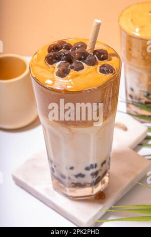 Boba dalgona Kaffee. Trendiges asiatisches Latte-Morgengetränk mit Instant-Kaffee und Tapioka-Perlkugeln, thailändisches Schaumcocktail-Glas im Sommer in der Sonne Stockfoto