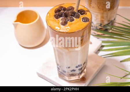 Boba dalgona Kaffee. Trendiges asiatisches Latte-Morgengetränk mit Instant-Kaffee und Tapioka-Perlkugeln, thailändisches Schaumcocktail-Glas im Sommer in der Sonne Stockfoto