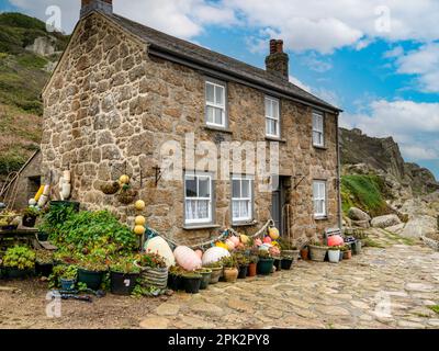 Attraktive alte Granitsteinhütte am Meer in Cornish mit Schieferdach und Fischerboote und Bojen in Penberth Cove, Cornwall, Großbritannien Stockfoto