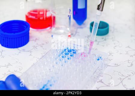 Wissenschaftler Arzt Pipettieren Proben im Labor mit vielen wissenschaftlichen Dingen - Becher, Zylinder, Pipette, Flüssigkeiten, Fläschchen, Ampulle, Ständer und mehr Stockfoto
