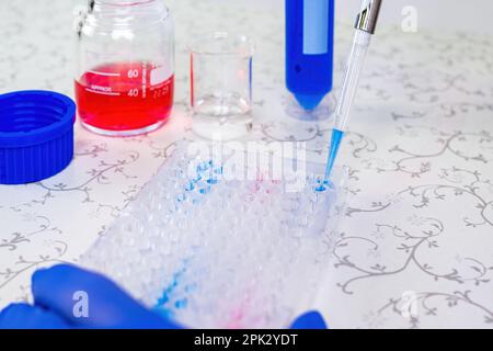 Wissenschaftler Arzt Pipettieren Proben im Labor mit vielen wissenschaftlichen Dingen - Becher, Zylinder, Pipette, Flüssigkeiten, Fläschchen, Ampulle, Ständer und mehr Stockfoto