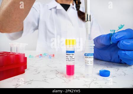 Wissenschaftler Arzt Pipettieren Proben im Labor mit vielen wissenschaftlichen Dingen - Becher, Zylinder, Pipette, Flüssigkeiten, Fläschchen, Ampulle, Ständer und mehr Stockfoto