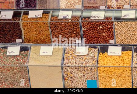 Trockenobst und verschiedene Gewürze in Plastikboxen, die auf dem Marktstand verkauft werden Stockfoto