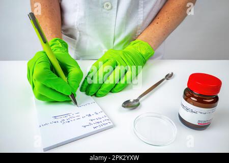 Der Wissenschaftlerarzt schreibt während seiner Recherche Notizen in ein Notizbuch neben dem Fläschchen mit Proben Stockfoto