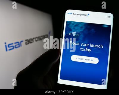 Person, die ein Mobiltelefon mit einer Webseite der Firma Isar Aerospace Technologies GmbH auf dem Bildschirm vor dem Logo hält. Konzentrieren Sie sich auf die Mitte des Telefondisplays. Stockfoto