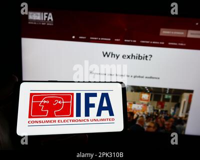 Person, die ein Smartphone mit dem Logo der Internationalen Funkausstellung Berlin (IFA) auf dem Bildschirm vor der Website hält. Konzentrieren Sie sich auf das Display des Telefons. Stockfoto