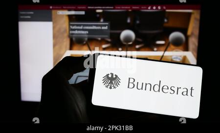 Handybesitzer mit dem Siegel des deutschen Bundesrats auf dem Bildschirm vor der Webseite. Konzentrieren Sie sich auf das Display des Telefons. Stockfoto