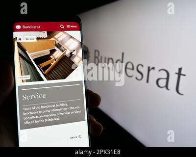 Person, die ein Smartphone mit Webseite des Bundesrats auf dem Bildschirm vor dem Siegel hält. Konzentrieren Sie sich auf die Mitte des Telefondisplays. Stockfoto