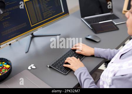 Großaufnahme einer jungen Frau, die über die Tastatur tippt, während sie Code in einem modernen Büro schreibt, Kopierraum Stockfoto