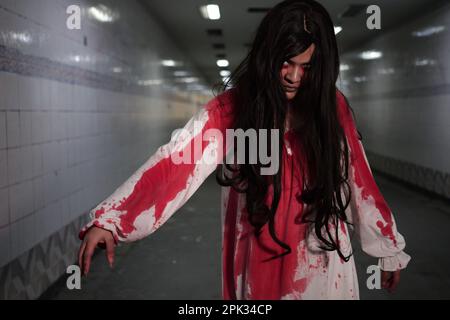 Unheimliche Frau in weißem Kleid mit Blutflecken nach Mord, Halloween-Konzept Stockfoto