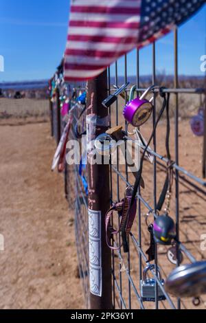 Sammlung von Vorhängeschlössern und einer amerikanischen Flagge auf einem Metallzaun in der Wüste von West Texas Stockfoto