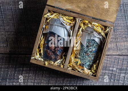 Glasbecher mit Blumentee und Glasbecher mit Kiefernkonfitüre in einer hölzernen Geschenkbox auf einem Tisch, Nahaufnahme. Schönes Geschenk für Familie und Freunde Stockfoto