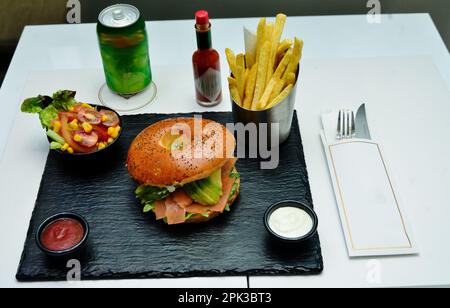 Burger Sandwich mit Lachs, Frischkäse, Avocado und Arugula auf hellem Hintergrund, Konzept Diätkost, Mitnehmen, gesundes Fast-Food Stockfoto