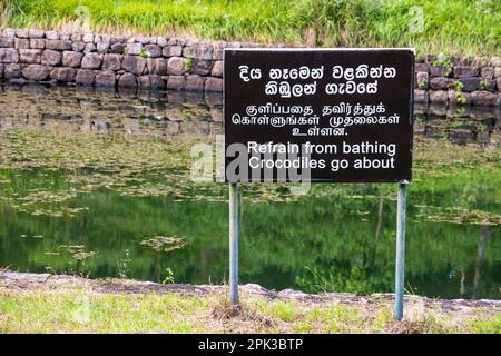 Ein Schild zur Warnung vor Krokodilen im Wasser bei Sigiriya in Sri Lanka Stockfoto