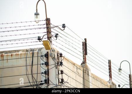 Elektrischer Zaun und hohe Betonwand. Hochspannungszaun im Gefängnis. Stacheldraht-Sicherheitszaun. Rasierdraht-Gefängniszaun. Gefängnis wegen Verhaftung Stockfoto