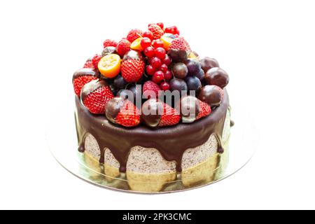 Kuchen mit Erdbeeren in geschmolzener Schokolade, Himbeere, Heidelbeere und roter Johannisbeere. Isoliert auf einfachem Hintergrund Stockfoto