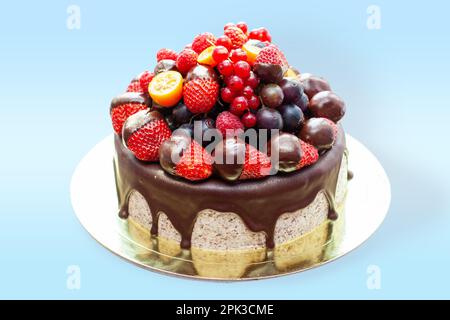 Kuchen mit Erdbeeren in geschmolzener Schokolade, Himbeere, Heidelbeere und roter Johannisbeere. Isoliert auf einfachem Hintergrund Stockfoto