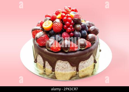 Kuchen mit Erdbeeren in geschmolzener Schokolade, Himbeere, Heidelbeere und roter Johannisbeere. Isoliert auf einfachem Hintergrund Stockfoto