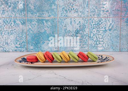 Bunte Makronen-Kuchen. Kleine französische Muffins. Süße und bunte französische Makronen. Bunte Makronen auf grauem Marmorhintergrund. Draufsicht. Pastellcolo Stockfoto