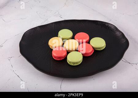 Bunte Makronen-Kuchen. Kleine französische Muffins. Süße und bunte französische Makronen. Bunte Makronen auf grauem Marmorhintergrund. Draufsicht. Pastellcolo Stockfoto