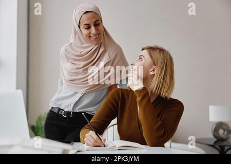Zwei lächelnde weibliche Kollegen im Büro, die zusammenarbeiten. Stockfoto