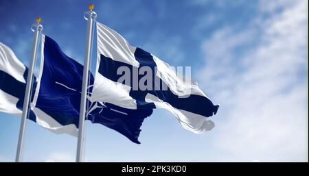 Brüssel, BL, April 2023: Die Flaggen Finnlands und der NATO winken im Wind. Finnland wurde am 4. April 2023 das 31. Mitglied der NATO. Anschauliche Bearbeitung Stockfoto