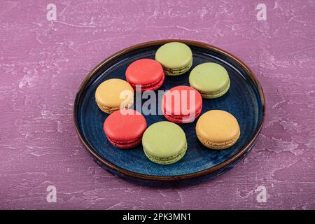 Bunte Makronen-Kuchen. Kleine französische Muffins. Süße und bunte französische Makronen. Bunte Makronen auf grauem Marmorhintergrund. Draufsicht. Pastellcolo Stockfoto