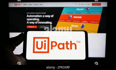 Person, die ein Mobiltelefon mit dem Logo des Automationssoftwareunternehmens UiPath Inc. Auf dem Bildschirm vor der Unternehmenswebseite hält. Konzentrieren Sie sich auf das Display des Telefons. Stockfoto