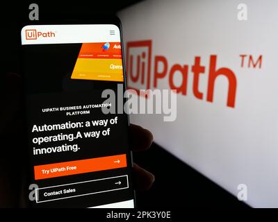Person, die ein Mobiltelefon mit einer Webseite des Automationssoftwareunternehmens UiPath Inc. Auf dem Bildschirm vor dem Logo hält. Konzentrieren Sie sich auf die Mitte des Telefondisplays. Stockfoto