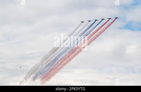 31. Juli 2022, St. Petersburg, Russland. Sukhoi Su-25 greift Flugzeuge an, die bei der Main Naval Parade in Rauch in den Farben der russischen Flagge abgegeben haben Stockfoto