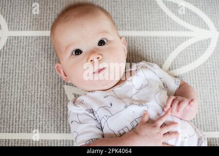 Süßes, weißes Mädchen auf der Spielmatte. Das erste Jahr des Babys Stockfoto