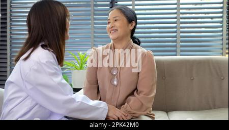 Lächelnde junge Ärztin, die sich mit einer glücklichen Seniorin unterhält Stockfoto