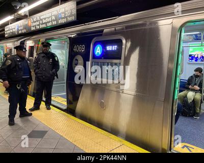 NYPD-Offiziere auf dem Bahnsteig vor einem A-Zug in der U-Bahn in New York am Sonntag, den 2. April 2023. (© Frances M. Roberts) Stockfoto