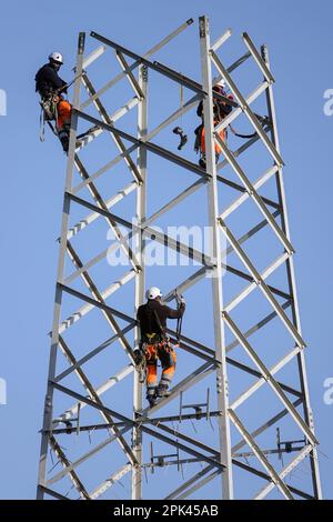 Elektriker arbeiten über Kopf, um einen Hochspannungspylon zum Austausch zu zerlegen. Mailand, Italien - April 2023 Stockfoto