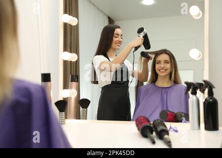 Stylistin trocknet die Haare des Kunden im Schönheitssalon Stockfoto