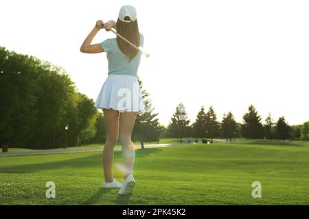 Eine Frau, die Golf auf einem grünen Golfplatz spielt, Rückansicht. Platz für Text Stockfoto