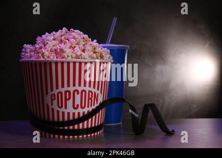 Köstliches Popcorn, Getränk und Klebeband auf dem Tisch. Platz für Text Stockfoto