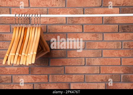 Kleiderbügel aus Holz in der Nähe von roten Backsteinwänden. Platz für Text Stockfoto