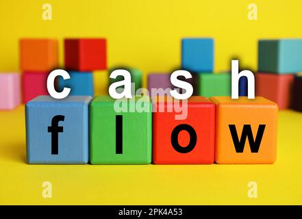 Text Cashflow mit Buchstaben und bunten Würfeln auf gelbem Hintergrund Stockfoto