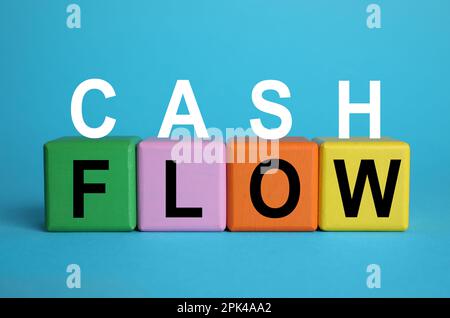 Satz Cashflow mit Buchstaben und bunten Würfeln auf hellblauem Hintergrund Stockfoto