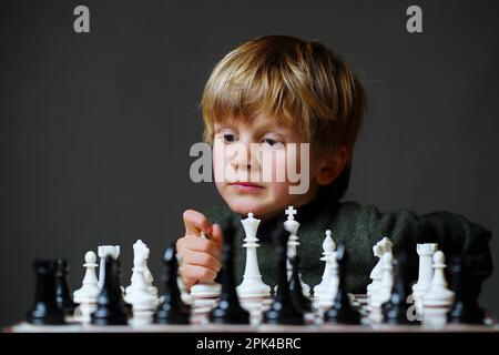 Konzentriertes Kind entwickelt Schachstrategie, spielt Brettspiel mit einem Freund, süßer kleiner Junge spielt Schach Stockfoto